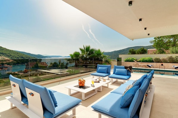 Une terrasse sur le toit dotée d’une piscine, de sièges rembourrés bleus et offrant une vue dégagée sur le paysage environnant.
