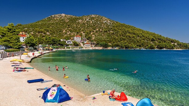 A beach with clear water, umbrellas, and a mountain in the background. - Luxury Villa Galatea Marina with Heated Pool (Marina)