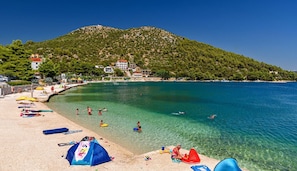 Une plage avec une eau cristalline, des parasols et une montagne en arrière-plan.