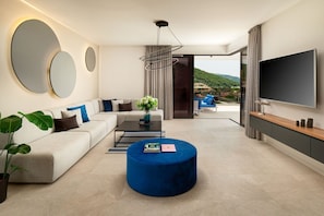 Un salon moderne avec un canapé, un pouf et un téléviseur à écran plat.