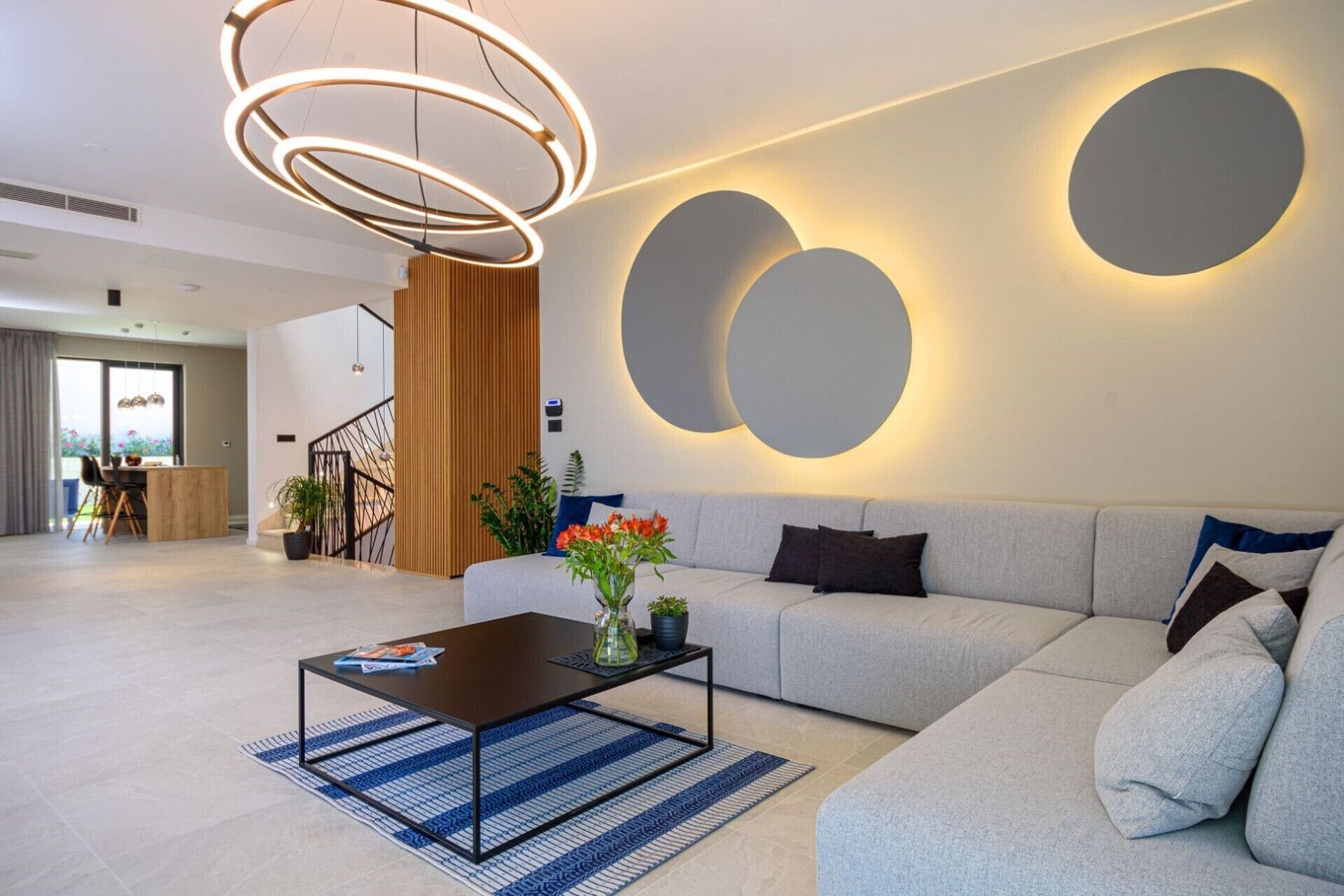 Una sala de estar moderna con un sofá, una mesa de centro, una lámpara colgante y luces circulares fijadas a la pared.
