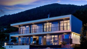 A modern two-story house with large windows, a balcony, and a view of a forested hill. - Luxury Villa Opatija Sapphire with Infinity Pool (Opatija)