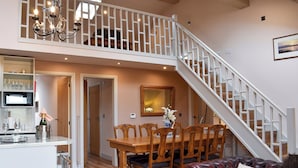 A spacious living area with a dining table, chairs, a leather sofa, a staircase, and a chandelier. - Roosters Rest - UK31826 (Barley, near Clitheroe)