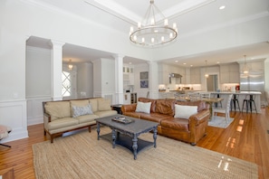 A spacious living room with a large sofa, a coffee table, and a chandelier.