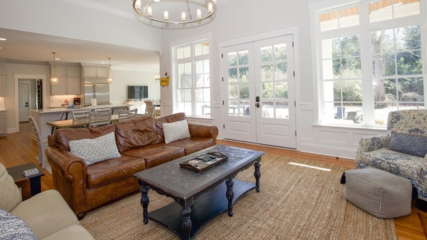 A spacious living room with a brown leather sofa, a coffee table, and a patterned armchair. - 600 Linden: 8  BR, 5.5  BA House in Pinehurst, Sleeps 20 (Pinehurst)