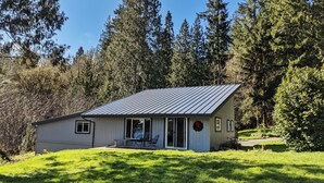 A small, single-story cabin with a metal roof, a porch, and a dining area.