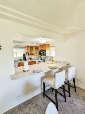 A modern kitchen with a central island, bar stools, and wooden cabinets. - 3br w/ beach access, large garden, beautiful views (Shelton)