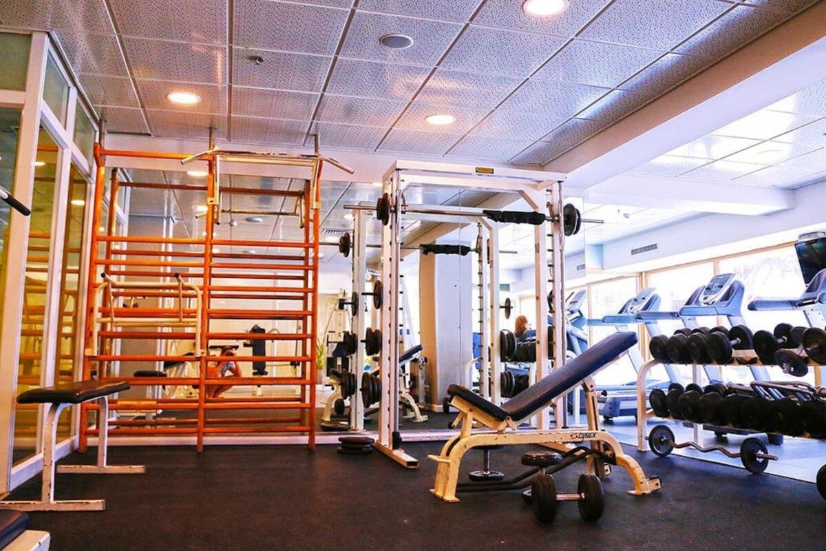 A gym with weightlifting equipment, benches, and dumbbells.
