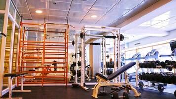 A gym with weightlifting equipment, benches, and dumbbells.