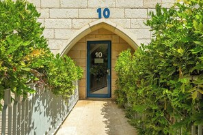 A building entrance with a number 10 sign above a door, surrounded by greenery.