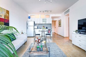 Un appartement moderne comprenant un salon, un coin repas, une cuisine et un téléviseur situé à droite.