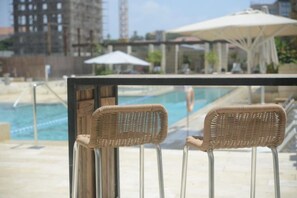 A poolside area with two wicker chairs and a pool in the background.
