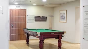 Une table de billard dans une pièce avec une porte et un panneau sur le mur.