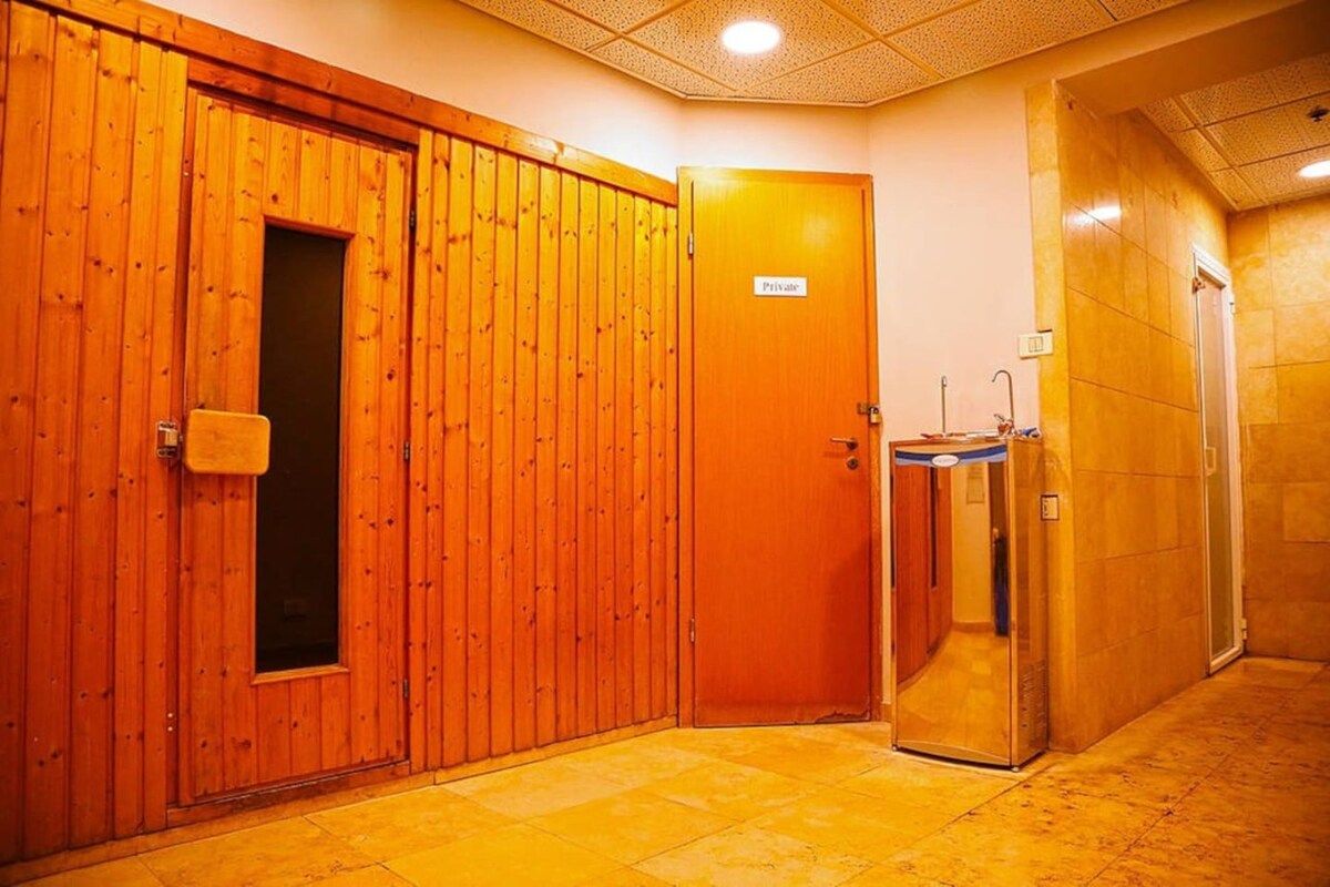 A hotel corridor with wooden doors, a private room sign, and a glass elevator.