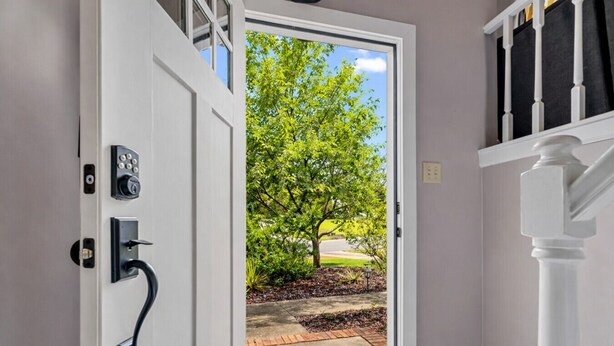 Una puerta que da a un jardín con un árbol y una banca.