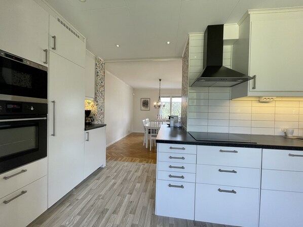 Una cocina moderna con armarios blancos, estufa negra y suelo de madera.