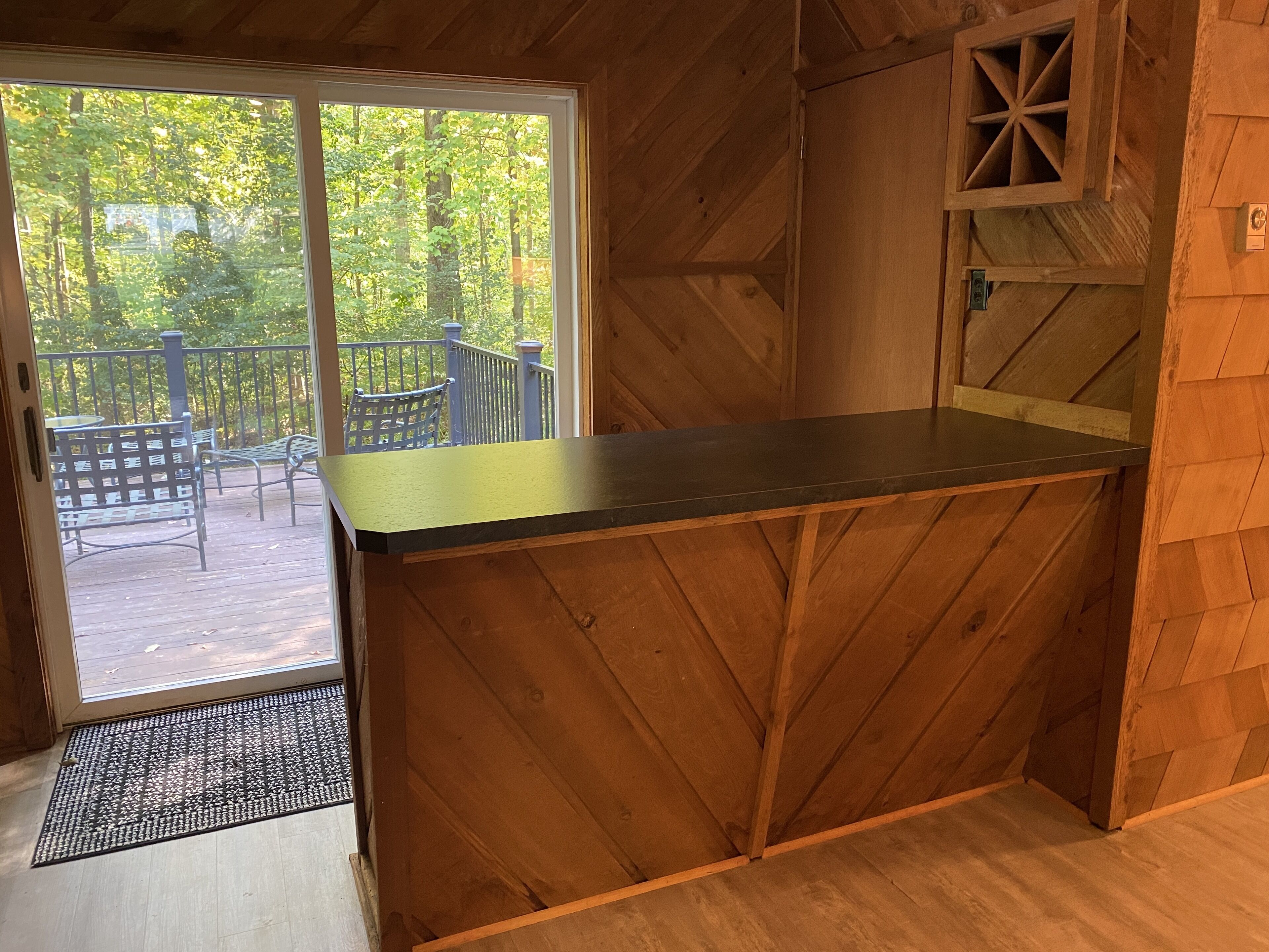 Un intérieur en bois avec une porte-fenêtre coulissante donnant sur une terrasse extérieure.