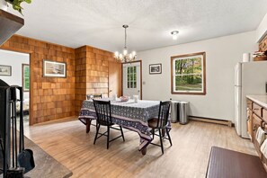 A dining area with a wooden wall, a chandelier, and a table with chairs. - Private Wooded Retreat close to Cornell (Freeville)