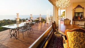 A dining area with a table and chairs, a chandelier, and a view of the sea. - Villa Stellare, with private pool and sea views (Capo d'Orlando)