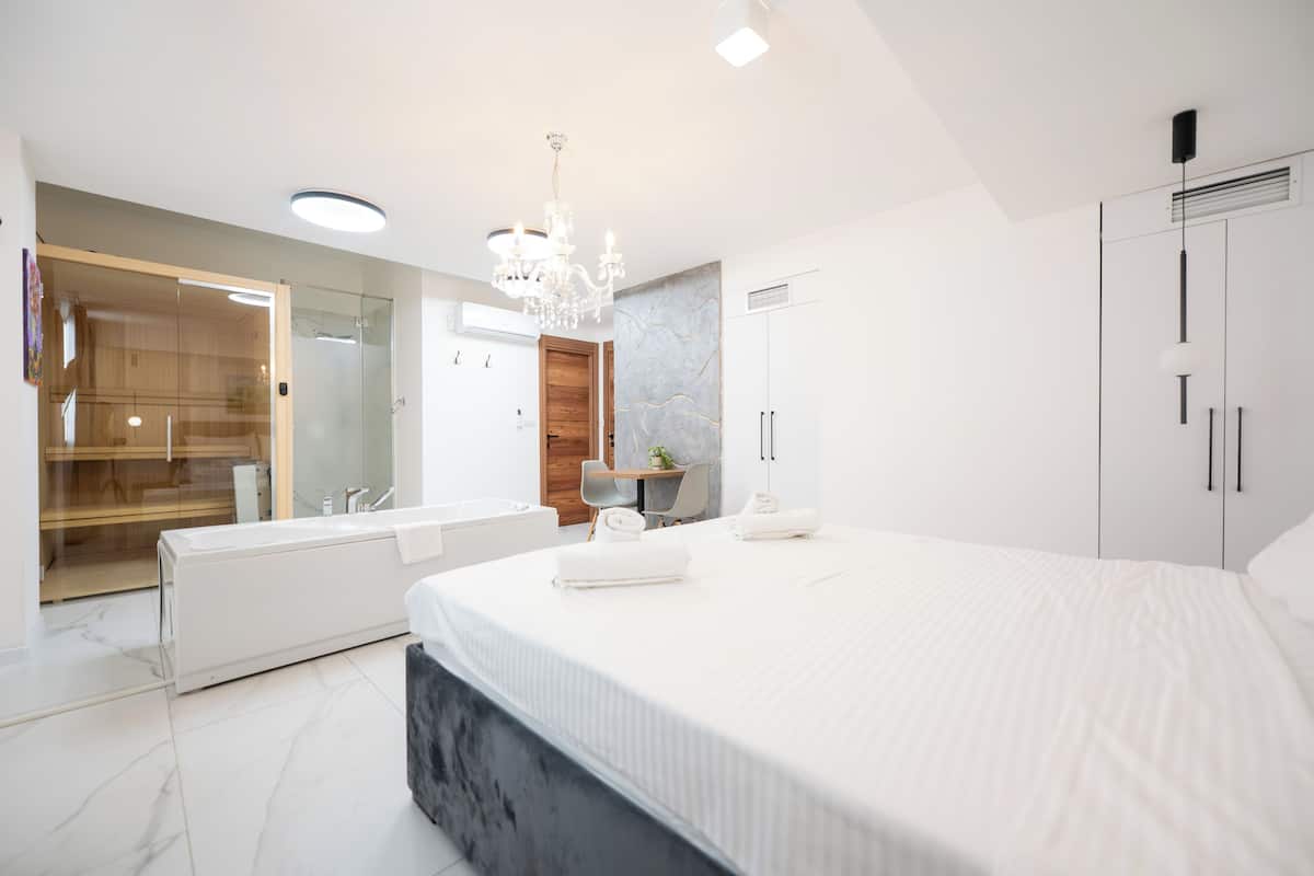 A modern bedroom with a large bed, a built-in shower, and a separate bathroom.