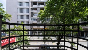 A view from a balcony with a metal railing, overlooking a street with parked cars and a building with multiple balconies in the background. - Kings Palace Suites (Belgrade)