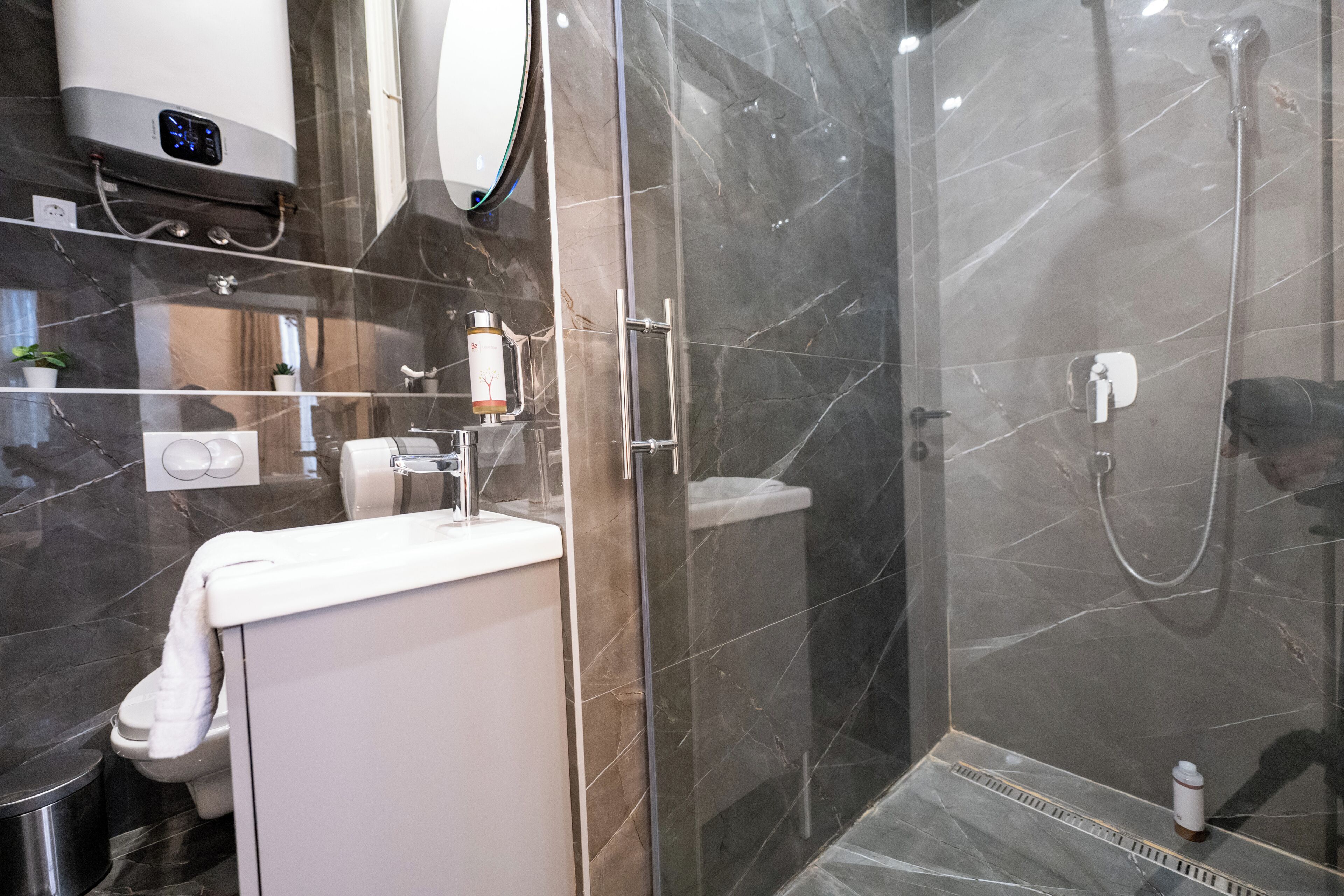 A modern bathroom with a glass-enclosed shower, a white sink, and a mirror above the sink.