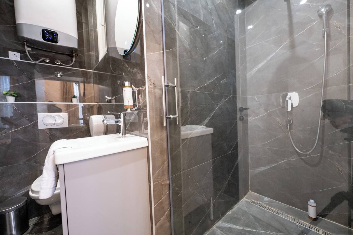 A modern bathroom with a glass-enclosed shower, a white sink, and a mirror above the sink.