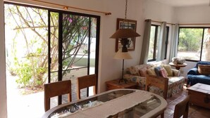 A dining area with a glass table, chairs, a sofa, and a lamp. - Casa Pájaros - Entire Lower Unit (Cabo Pulmo)