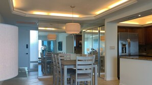 Eine moderne Küche mit integriertem Kühlschrank, einem Essbereich mit rundem Tisch und Stühlen sowie einem großen Fenster, das für natürliches Licht sorgt.