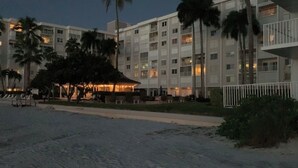 Ein mehrstöckiges Hotel mit Balkonen, Palmen und einem Strandabschnitt.
