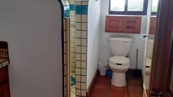 Une petite salle de bain comprenant des toilettes, une petite fenêtre et des murs carrelés.