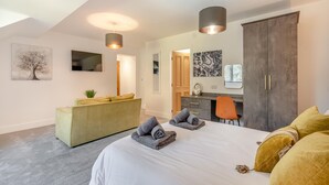A modern bedroom with a large bed, a desk, and a wardrobe.