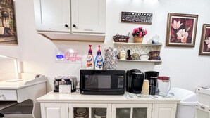 A kitchenette with a microwave, toaster, coffee maker, and various kitchen items on the counter. - Hutchinson Haven of Rest (Hutchinson)