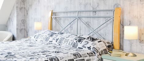 A bedroom with a bed, a nightstand, a lamp, and a chair.