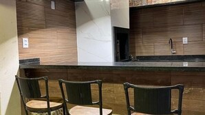 Un área de bar con mostrador, tres taburetes y lámparas colgantes.