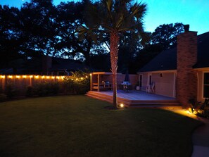 A backyard with a wooden deck, a palm tree, and string lights. - THE BIG KAHUNA, close to Shem Creek, Sullivans Island and Historic Charleston! (Mount Pleasant)