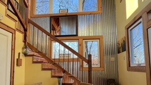 A wooden staircase leading to a second floor with a view of bare trees. A round wooden table with two chairs is in the foreground. - Majestic Views, Romantic Brow Home 1.5 Miles From The Heart Of Mentone (Mentone)