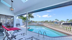 Zona junto a la piscina con sillas de descanso y vista al agua.