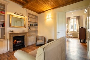 A living room with a fireplace, bookshelves, a sofa, and a dining area with a table and chairs.