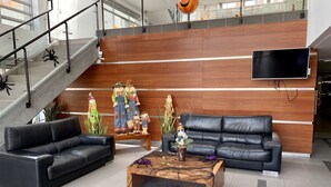 A lobby with two black leather sofas, a wooden coffee table, and a reception desk with a wooden backdrop. - WOW! NEW 3/2BR, NEAR AIRPORT & SHOPPING - PREMIUM! (Bogotá)