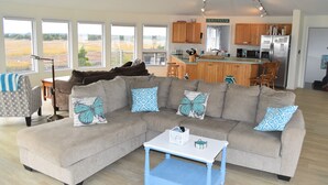 A spacious living room with a sectional sofa, a coffee table, and a view of the outdoors. - Family friendly home w/  360 views of the bay and wild life preserve (Milton)