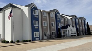 A row of multi-story residential buildings with a flat roof, a flagpole with an American flag, and a clear sky. - Microtel Inn&Suites by Wyndham (Springfield)
