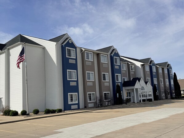 A row of multi-story residential buildings with a flat roof, a flagpole with an American flag, and a clear sky. - Microtel Inn&Suites by Wyndham (Springfield)