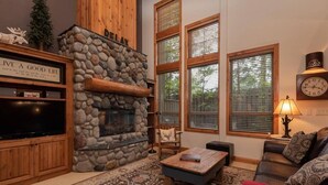 Una sala de estar acogedora con chimenea de piedra, televisor y una zona de estar confortable.