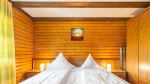 Una stanza con rivestimento in legno, un letto, due comodini e un quadro appeso al muro.