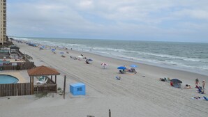 Una playa con zona de piscina, sombrillas y sillas.