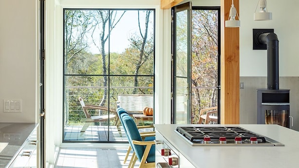 A modern kitchen with a large island, wooden beams, and a view of the outdoors.