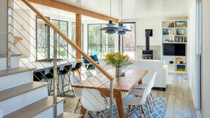 A modern kitchen with a wooden staircase, a dining area with a table and chairs, and a built-in TV shelf.