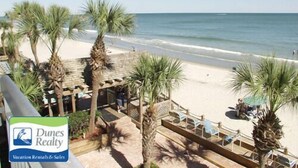 A beach view with palm trees and a wooden deck. - Water's Edge Resort #210 - Oceanfront in Garden City Beach, SC (Garden City)