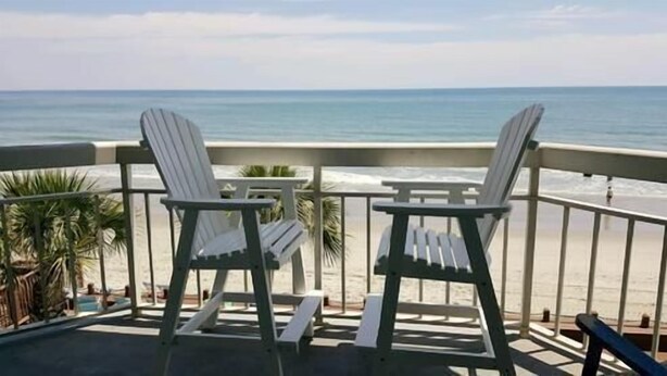 Two Adirondack chairs on a balcony overlooking a beach with a railing. - Water's Edge Resort #210 - Oceanfront in Garden City Beach, SC (Garden City)